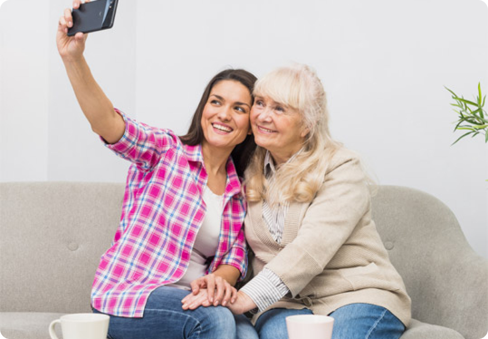 Una señora mayor y una joven sacándose una fotografía en el sofá